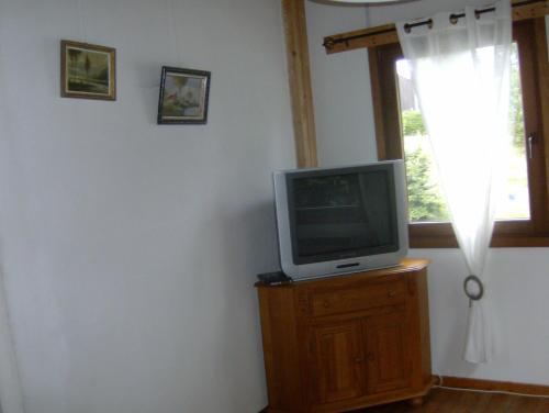 a tv sitting on top of a wooden stand next to a window at La Maison en Bois in Wibrin