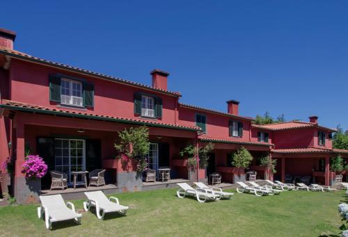 a large red building with white chairs and tables at Quinta Santo Antonio Da Serra in Santa Cruz