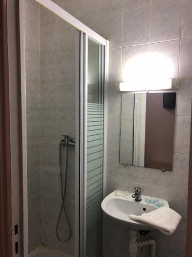 ein Bad mit einer Dusche, einem Waschbecken und einem Spiegel in der Unterkunft Hotel Chevallier in Levallois-Perret