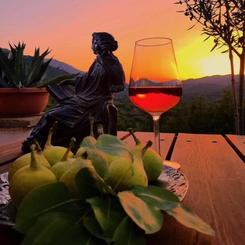 a glass of wine sitting on a table with a statue at Helicon Muses Friendly Mountain B&B Guesthouse in Evangelístria