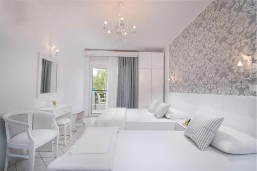 a white bedroom with two beds and a chandelier at Studios Filipidis in Chrysi Ammoudia
