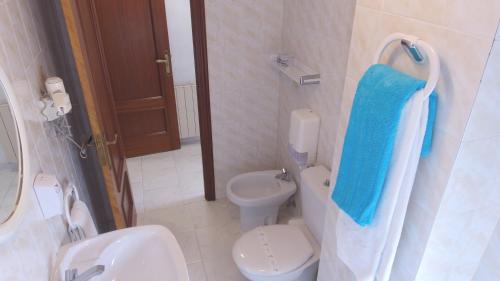 a bathroom with a toilet and a blue towel at Hotel Candano in Isla