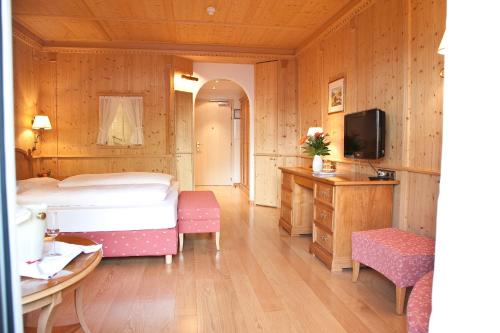 a bedroom with a bed and a tv in a room at Hotel Grüner Baum in Bressanone