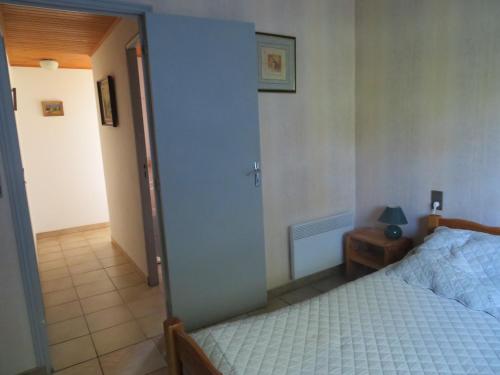 een slaapkamer met een bed en een deur naar een gang bij CHAMBRE D'HOTES LES MENHIRS in Moulin-Mage