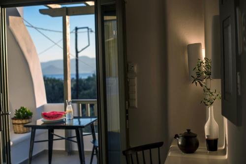 a room with a table and a balcony with a view at Melidron Hotel & Suites in Agios Prokopios