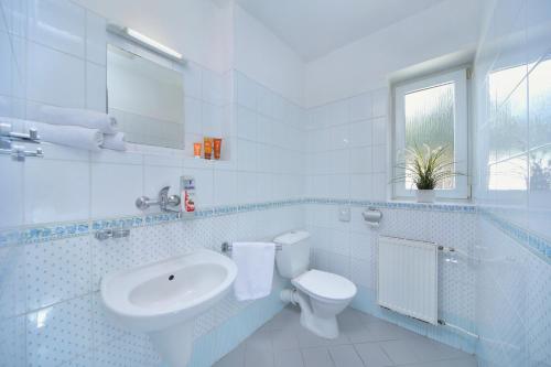 a white bathroom with a sink and a toilet at Hotel Lenka in Špindlerův Mlýn