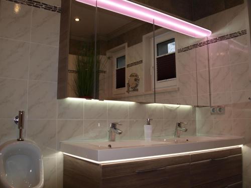 een badkamer met een wastafel en een grote spiegel bij Macke`s Ferienwohnungen in Hahnenklee-Bockswiese