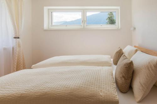 a white bedroom with two beds and a window at Apartment im Huggn in Fulpmes