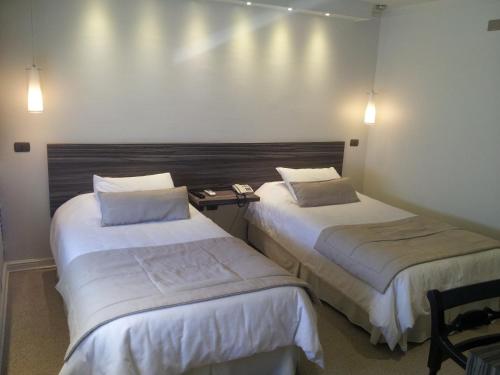 two beds in a room with lights on the wall at Hotel Las Terrazas Business in Chillán