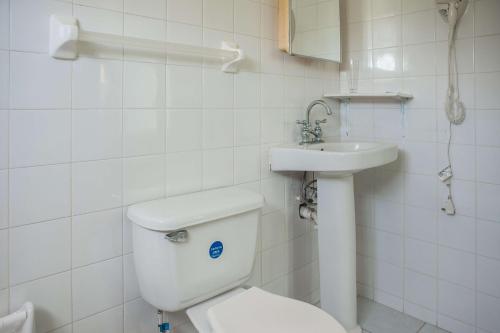 a white bathroom with a toilet and a sink at Diamond Villa Guest House in Montego Bay