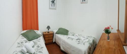 a bedroom with two beds and a table with a vase of flowers at Apartamentos Casa María in Agulo