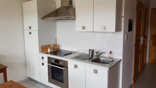 une cuisine avec des armoires blanches et un évier dans l'établissement F2 SUR LES HAUTEURS DE GERARDMER, à Gérardmer