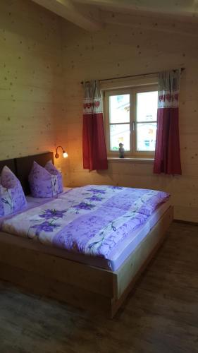a bedroom with a bed with purple sheets and a window at Haus Franz und Haus Antje in Schönau am Königssee