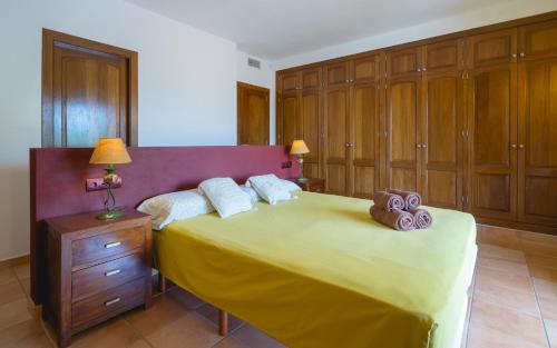 - une chambre avec un grand lit jaune et des placards en bois dans l'établissement Can Roig, à Santa Gertrudis de Fruitera