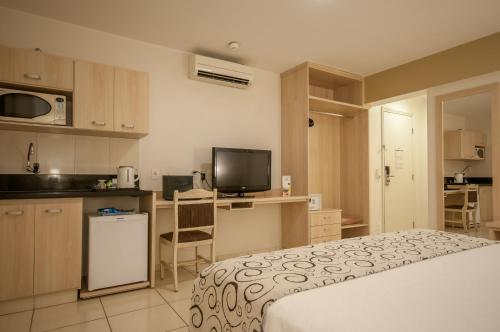 a bedroom with a bed and a kitchen with a tv at Saint Peter Hotel São Jose do Rio Preto in Sao Jose do Rio Preto