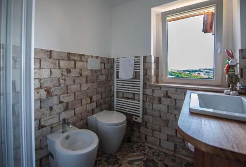 a bathroom with a sink and a toilet and a window at B&B Madonna Carradori Country in Offagna