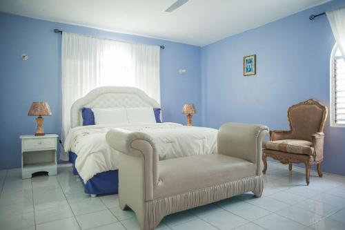 a blue bedroom with a bed and a chair at Diamond Villa Guest House in Montego Bay