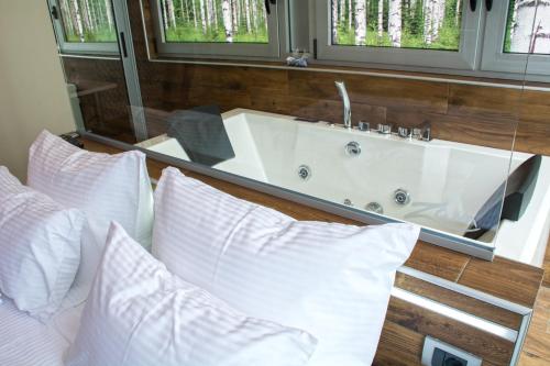 um quarto com uma banheira e uma cama com almofadas em Zam Residence em Valjevo