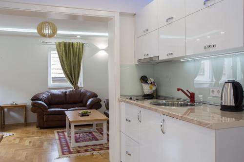 a kitchen with a sink and a couch in a room at Guest House Hendek in Sarajevo