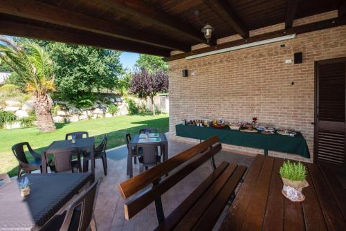 een patio met tafels en banken en een bakstenen muur bij B&B Madonna Carradori in Offagna