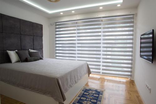 a bedroom with a large bed and a large window at Guest House Hendek in Sarajevo