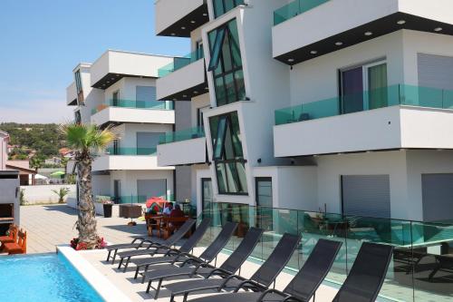 a swimming pool with lounge chairs next to a building at Boutique Apartments Ad Astra in Bibinje