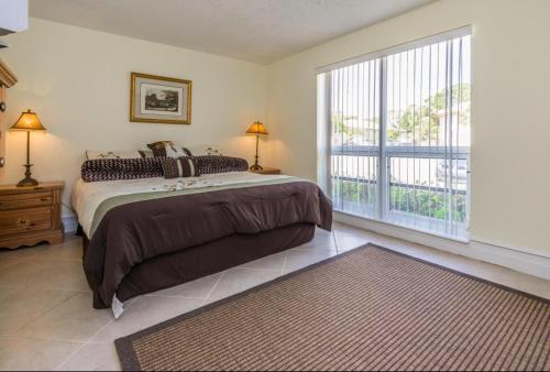 a bedroom with a bed and a large window at PGA National Resort Golf Villa - Luxurious Two Bedroom First Floor Water View in Palm Beach Gardens