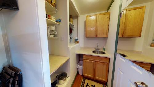 a small kitchen with wooden cabinets and a sink at Hot Tub, Kokopelli Kabyn, Cute and Cozy! in Blanding