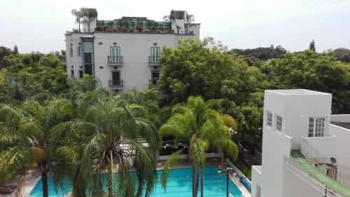 a building with a swimming pool and palm trees at The Lorian Club in Cocoyoc