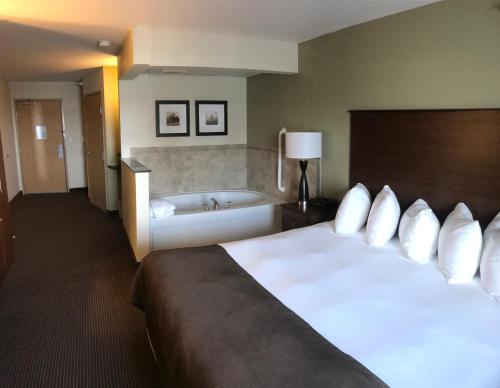 a hotel room with a large bed and a bath tub at AmericInn by Wyndham Osage in Osage
