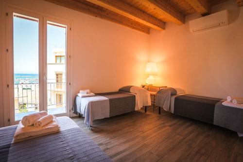 a room with three beds and a large window at B&B Da Peppa in Castellammare del Golfo