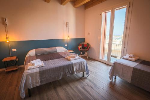 a bedroom with two beds and a large window at B&B Da Peppa in Castellammare del Golfo