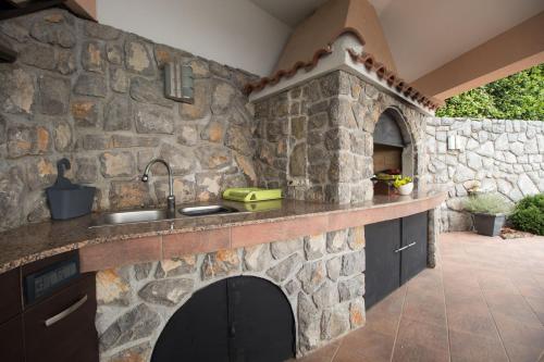 a stone kitchen with a sink and a fireplace at Apartments Villa Adore in Ičići