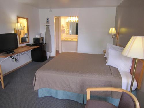 Habitación de hotel con cama, escritorio y TV. en Cassville Budget Inn, en Cassville