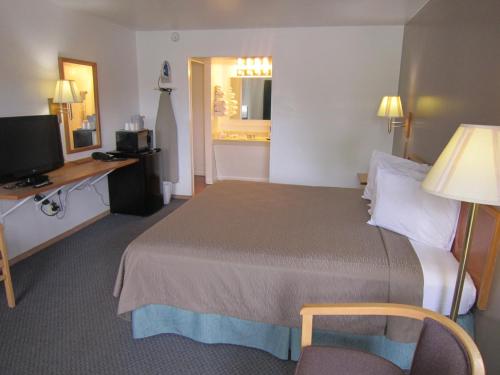 a hotel room with a bed and a desk and a television at Cassville Budget Inn in Cassville