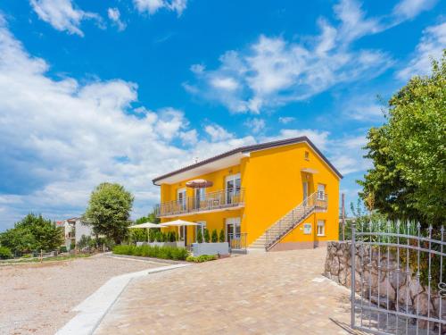 ein gelbes Haus mit einem Balkon und einem Zaun in der Unterkunft Appartments Adriatic in Omišalj