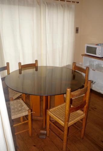 a glass table with two chairs and a microwave at Cabañas 4 Esquinas in La Serena