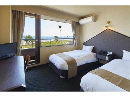 Pals Inn Katsuura في كاتسورا: غرفة فندقية بسريرين وإطلالة على المحيط