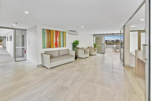 a living room with a couch and chairs on a tile floor at Aquarius Kawana in Kawana Waters