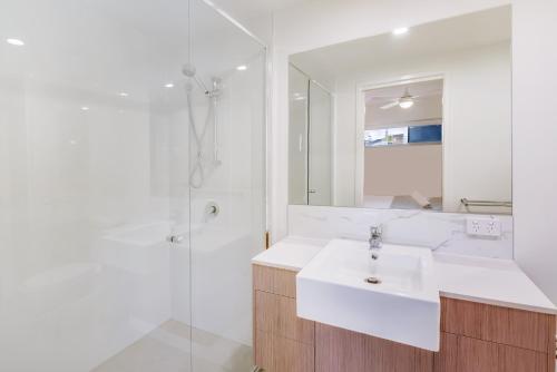 a white bathroom with a sink and a shower at Aquarius Kawana in Kawana Waters