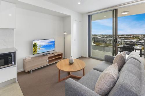 a living room with a couch and a tv at Aquarius Kawana in Kawana Waters