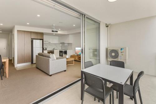 a dining room and living room with a table and chairs at Aquarius Kawana in Kawana Waters