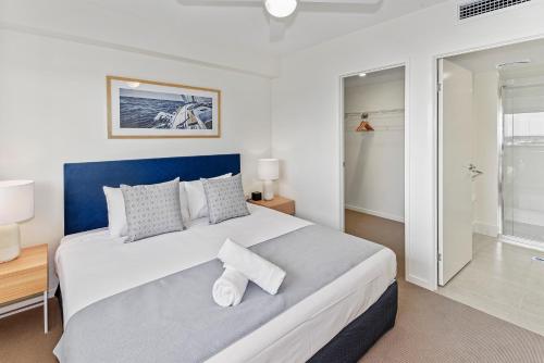 a bedroom with a large bed with a blue headboard at Aquarius Kawana in Kawana Waters