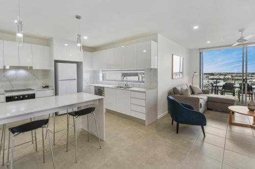 a kitchen and living room with a couch and a table at Aquarius Kawana in Kawana Waters