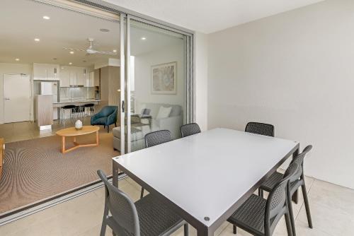 a dining room and living room with a table and chairs at Aquarius Kawana in Kawana Waters
