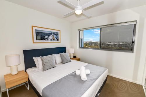 a bedroom with a large bed and two windows at Aquarius Kawana in Kawana Waters