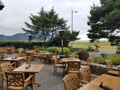 um restaurante com mesas e cadeiras de madeira e árvores em The Seaside Oceanfront Inn em Seaside