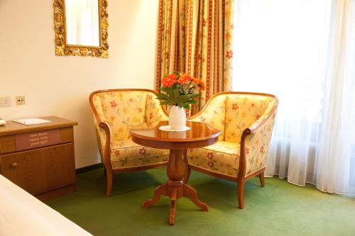 a room with a table and a chair and a vase of flowers at Hotel Grüner Baum in Bressanone