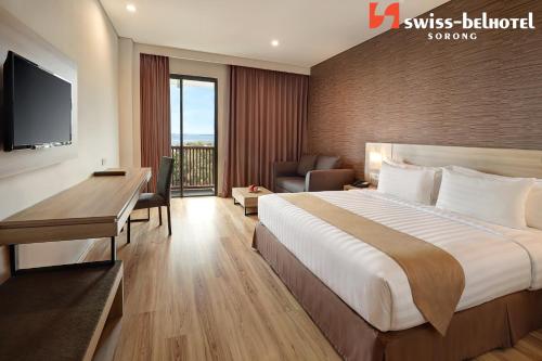 a hotel room with a bed and a desk and a television at Swiss-Belhotel Sorong in Sorong
