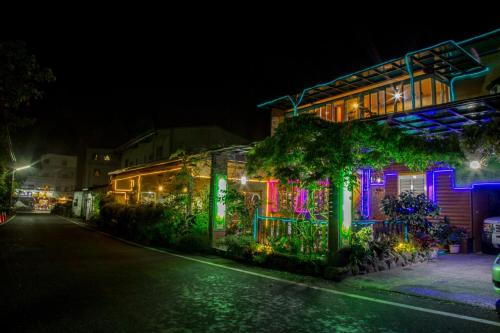 a house with colorful lights on a street at night at Rui Li Yinxiang Qu Homestay in Meishan